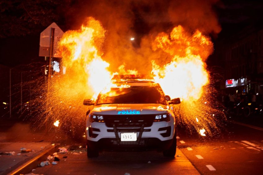 A police car with an explosion behind it