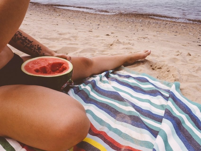 A woman at the beach with a watermelon