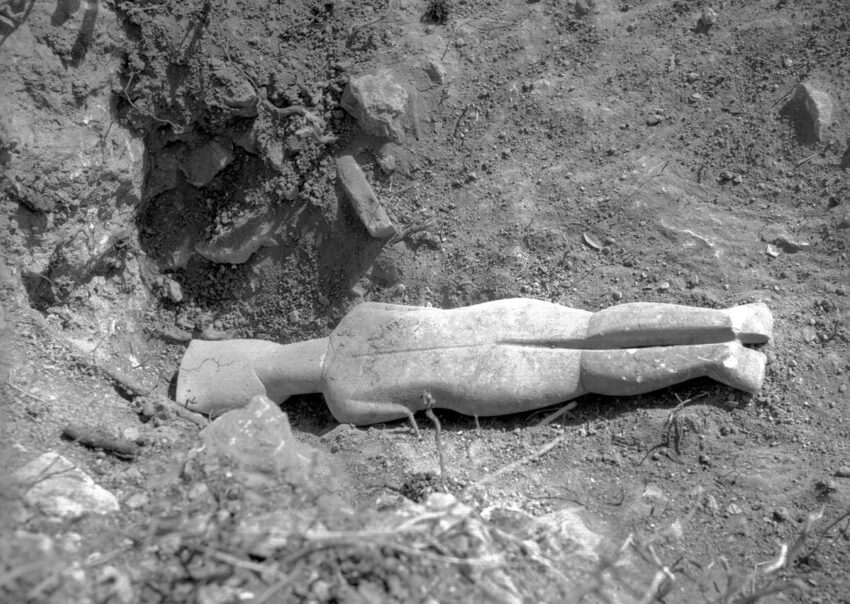 Grayscale image of an excavated Cycladic figure face down in the dirt on the island of Keros in July 1967