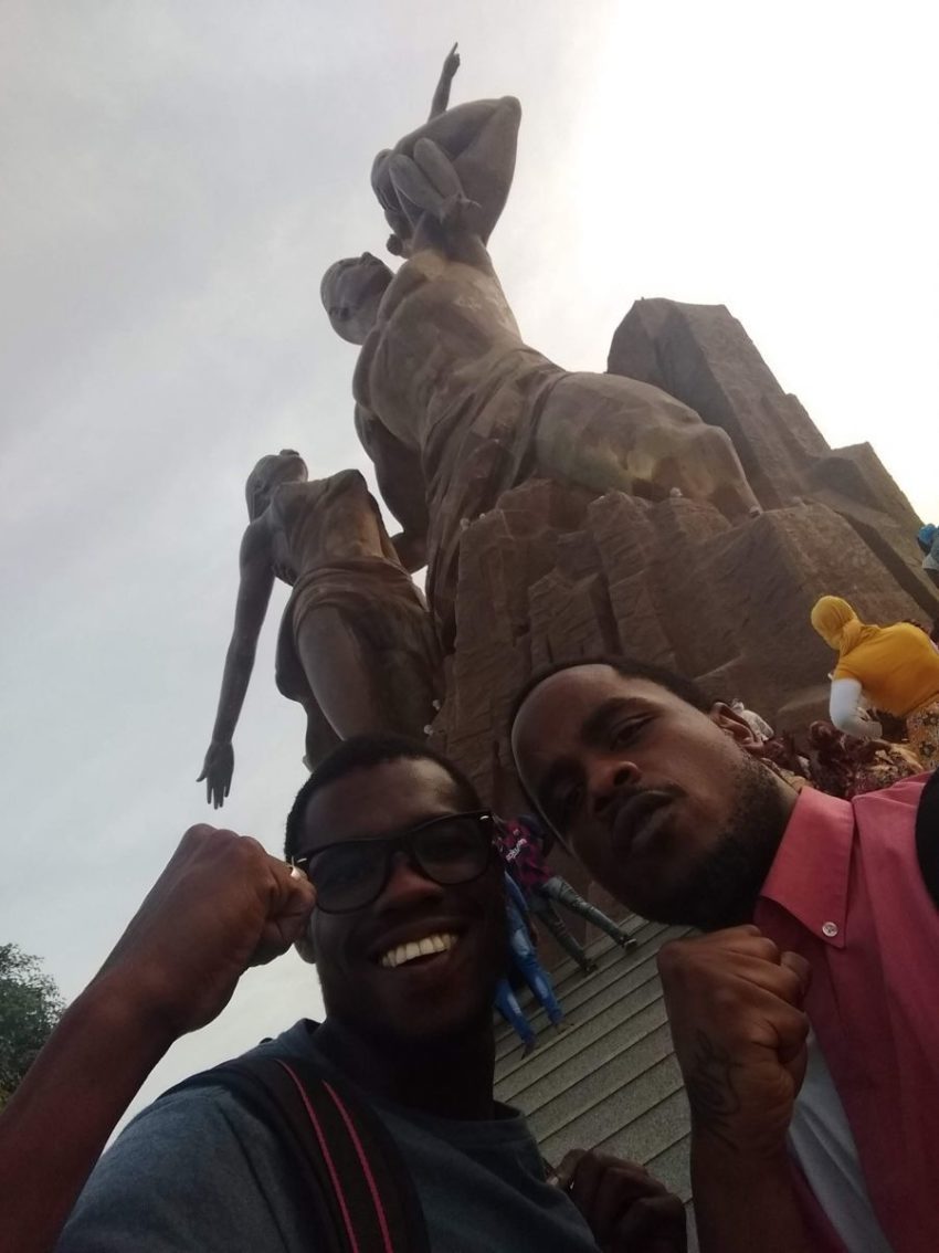image of author and Ceikh in front of Monument de la Renaissance Africaine