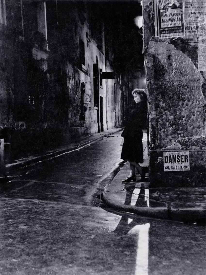 black and white photo of woman standing on street corner