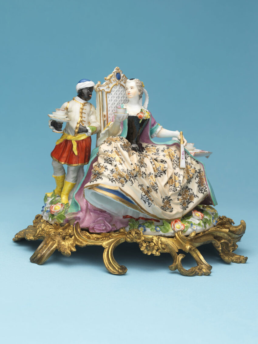 Porcelain figurine depicting a sumptuously dressed white woman exchanging admiring glances with her liveried Black attendant