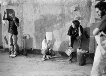 A group of people stand in various postures before a wall