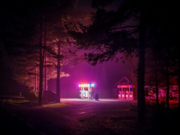 A gas station at night in the woods emanates pink light