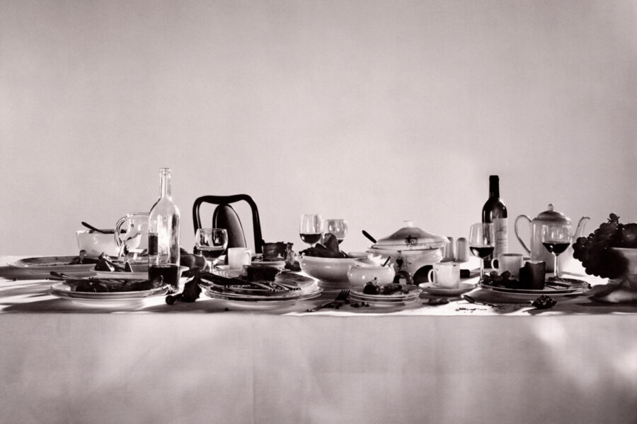 Grayscale image of a tablescape set with glasses of wine and an overflowing bowl of fruit