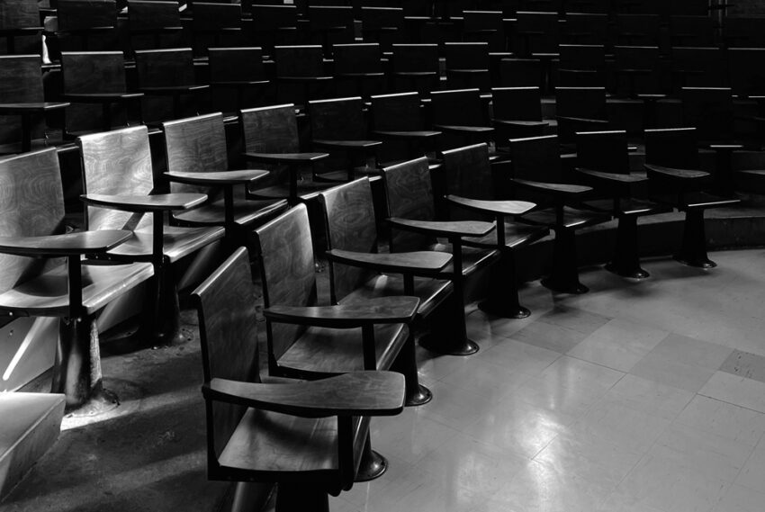 Black and white photograph of lecture hall desks in a semi-circle