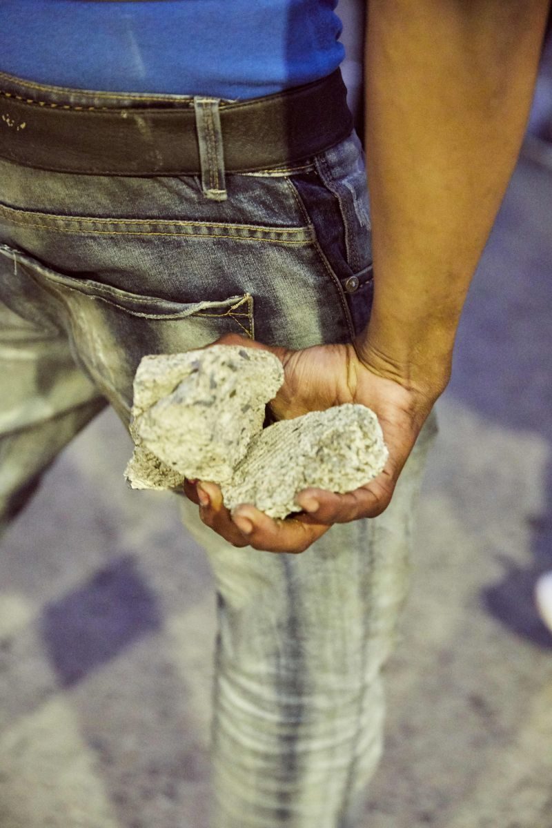 A person holds a handful of rocks behind his leg